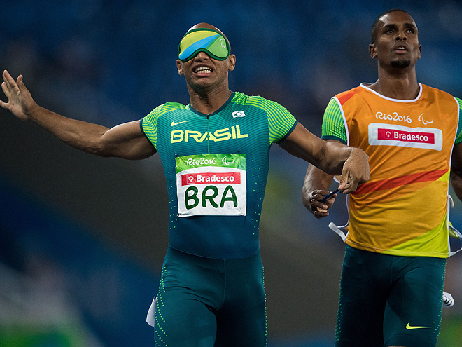 Felipe Gomes of Brazil with his guide Jonas de Lima Silva running the final leg of the men's 4x100m - T11-13 Round 1 Heat 1 in the Olympic Stadium during the Paralympic Games in Rio de Janeiro, Brazil on September 12, 2016. Handout photo by Bob Martin for OIS/IOC via AFP. RESTRICTED TO EDITORIAL USE. / AFP / IOS/OIC / Bob Martin for OIS (Photo credit should read BOB MARTIN FOR OIS/AFP/Getty Images)