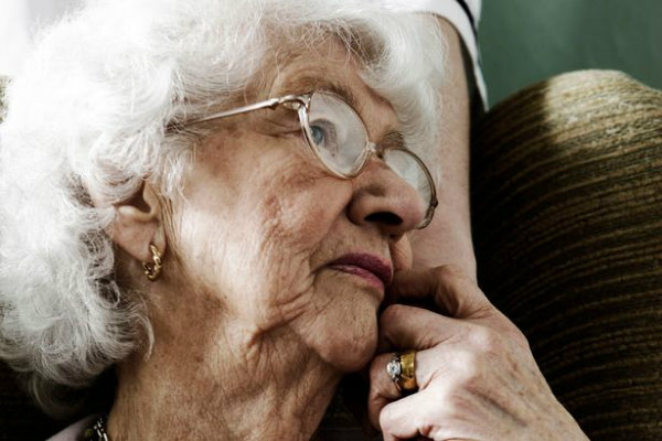 elderly-woman-sitting-in-chair-with-hand-of-care-worker-comforting-her-w600