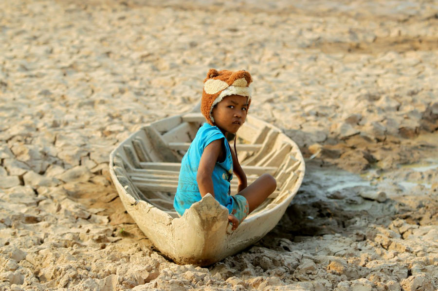 دختربچه ای که در قایقی در رودخانه خشک شده نشسته است، کامبوج - 13 می