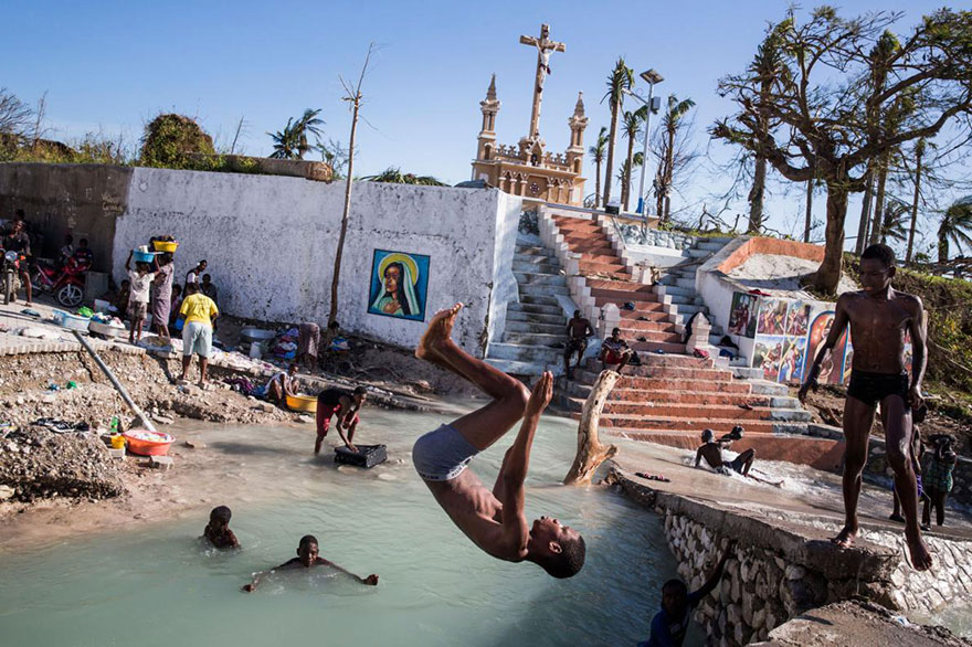2- کودکان در حال شنا کردن در کنار پل شکسته رودخانه ای در پورت سلو در هایتی هستند. این شهر در نتیجه توفان متیو آسیب جدی دیده و تقریبا تمامی ساختمان های آن از بین رفته اند.