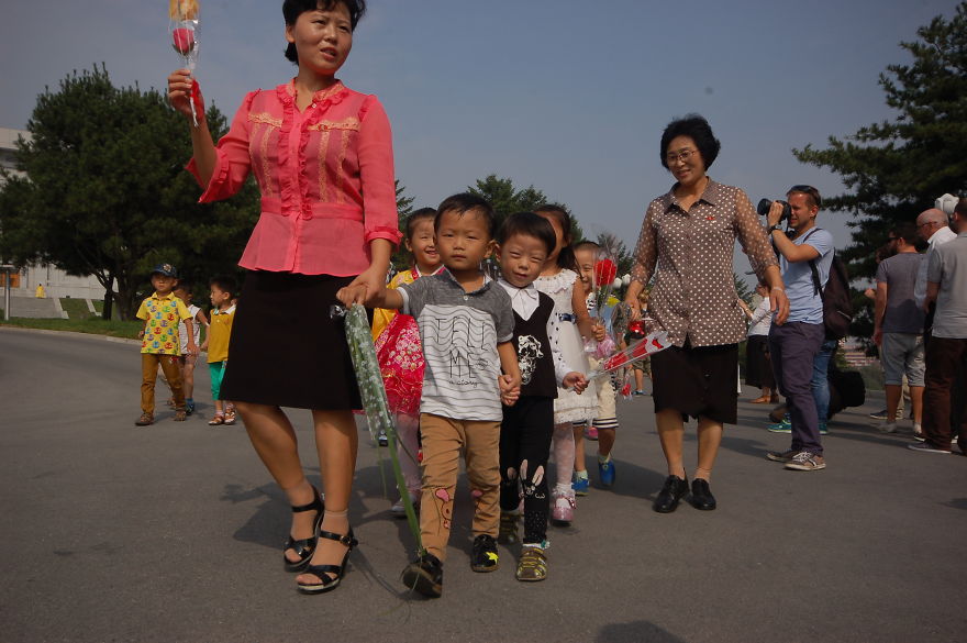 کودکانی که با گل در مسیر ادای احترام به کیم ایر سانگ و کیم جونگ ایل هستند. 
