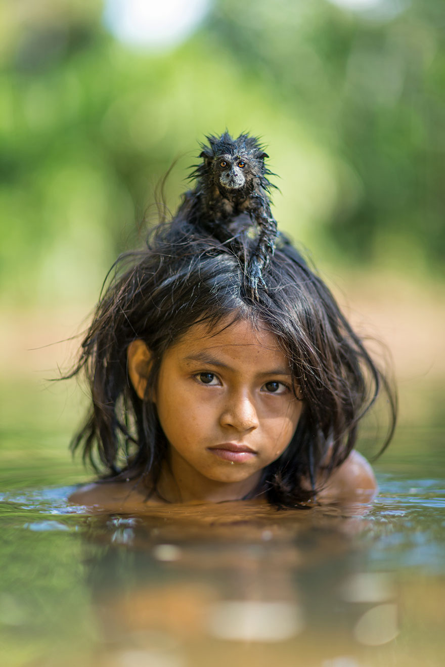 48- یک تامارین (بومی آمریکای جنوبی) روی سر دخترکی به نام «یوینا مامریا» نشسته است که درون رودخانه Yomibato مشغول بازی است. این رودخانه در پارک ملی Manú پرو واقع شده است.