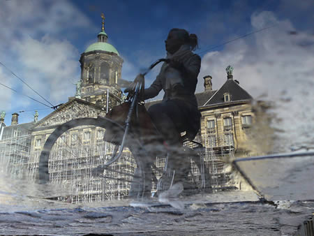 این تصویر با موبایل گرفته شده و هیچ ویرایش یا فیلتری روی آن صورت نگرفته است. این تصویر، از بازتاب سایه یک زن دوچرخه سوار در گودال آبی در مقابل کاخ سلطنتی در شهر آمستردام گرفته شده است.