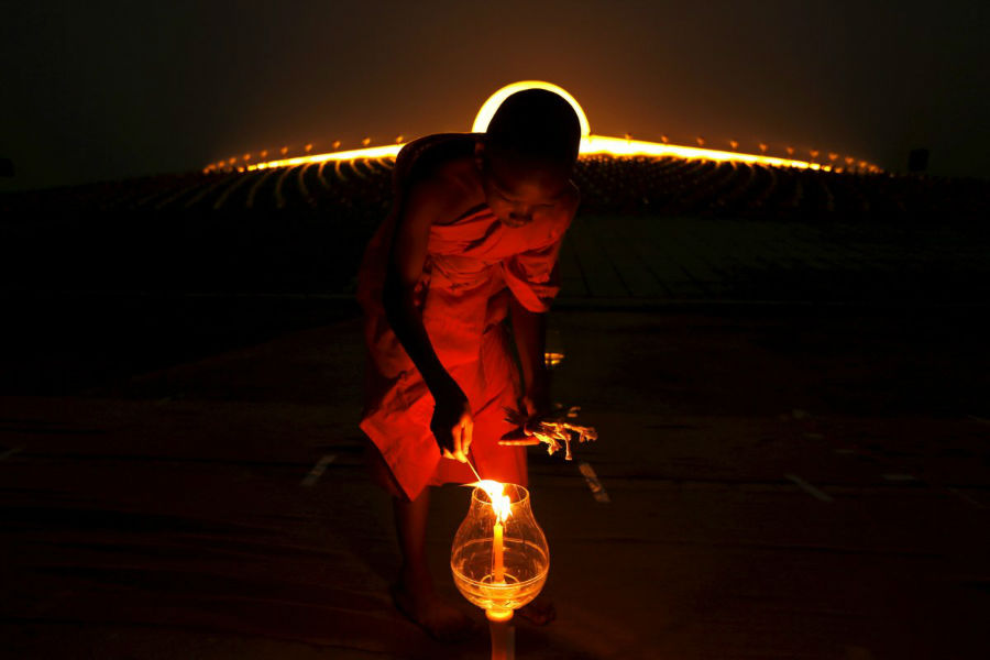 یک راهب بودائی در حال روشن کردن شمع در معبد Phra Dhammakaya در ایالت تانی در شمال بانکوک است - 22 فوریه 2016