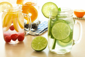 Detox water with various types of fresh fruit and vegetables in mason jars on a table