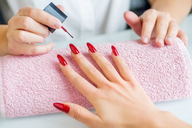 1 A woman with red painted nails getting a manicure