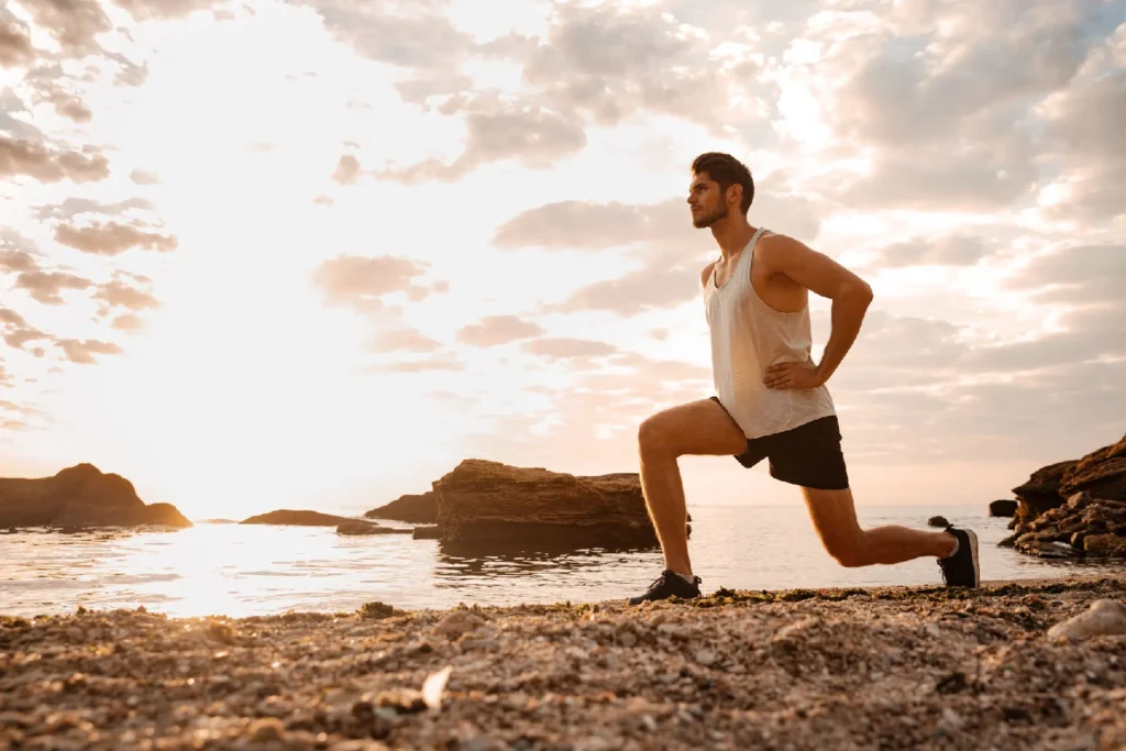 young healthy man athlete doing squats at the beach at sunset graphicstock 1024x683 - 5 عادتی که هر مردی باید هر روز انجام دهد تا به موفقیت برسد